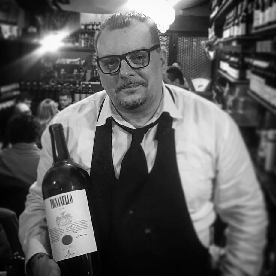 Stefano Cremonese in enoteca con una bottiglia di vino