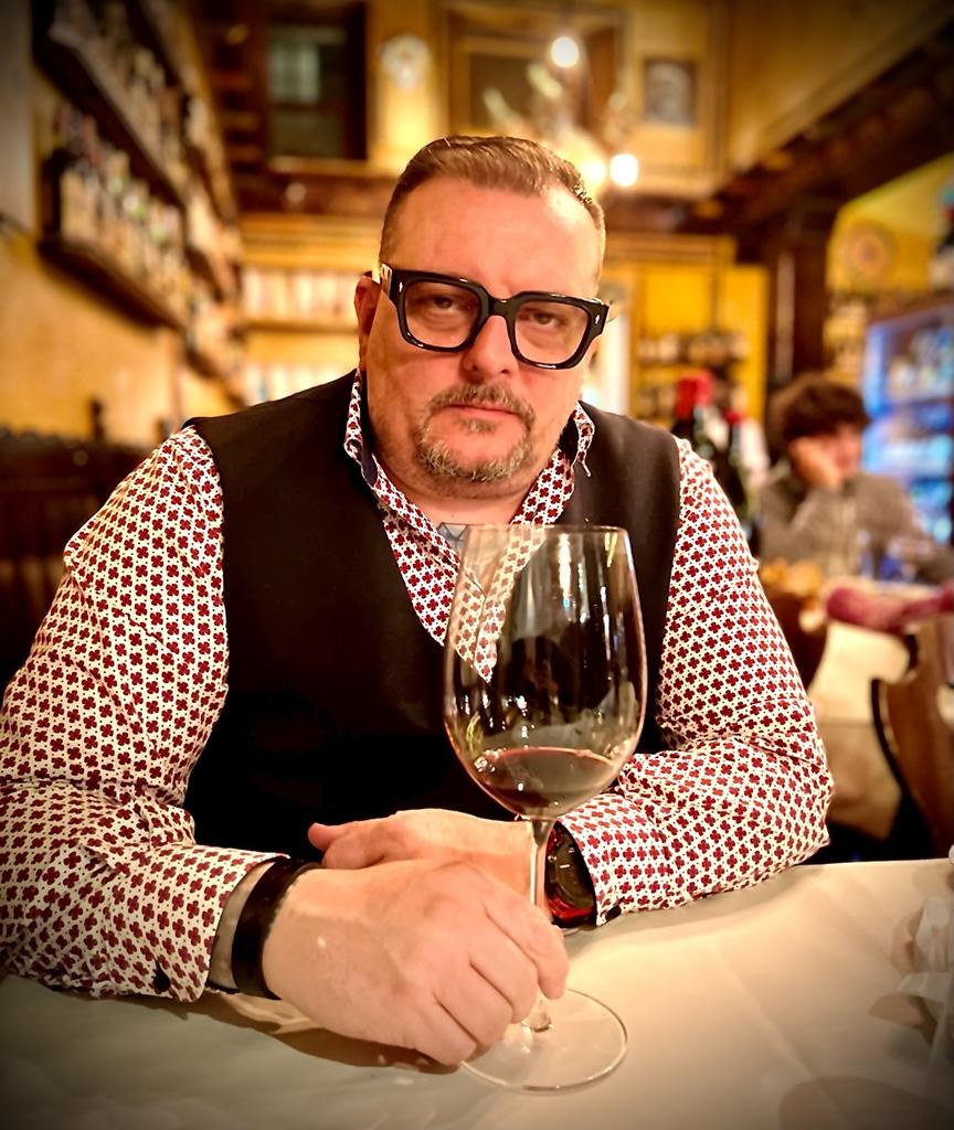 Stefano Cremonese al tavolo di un ristorante con un calice di vino